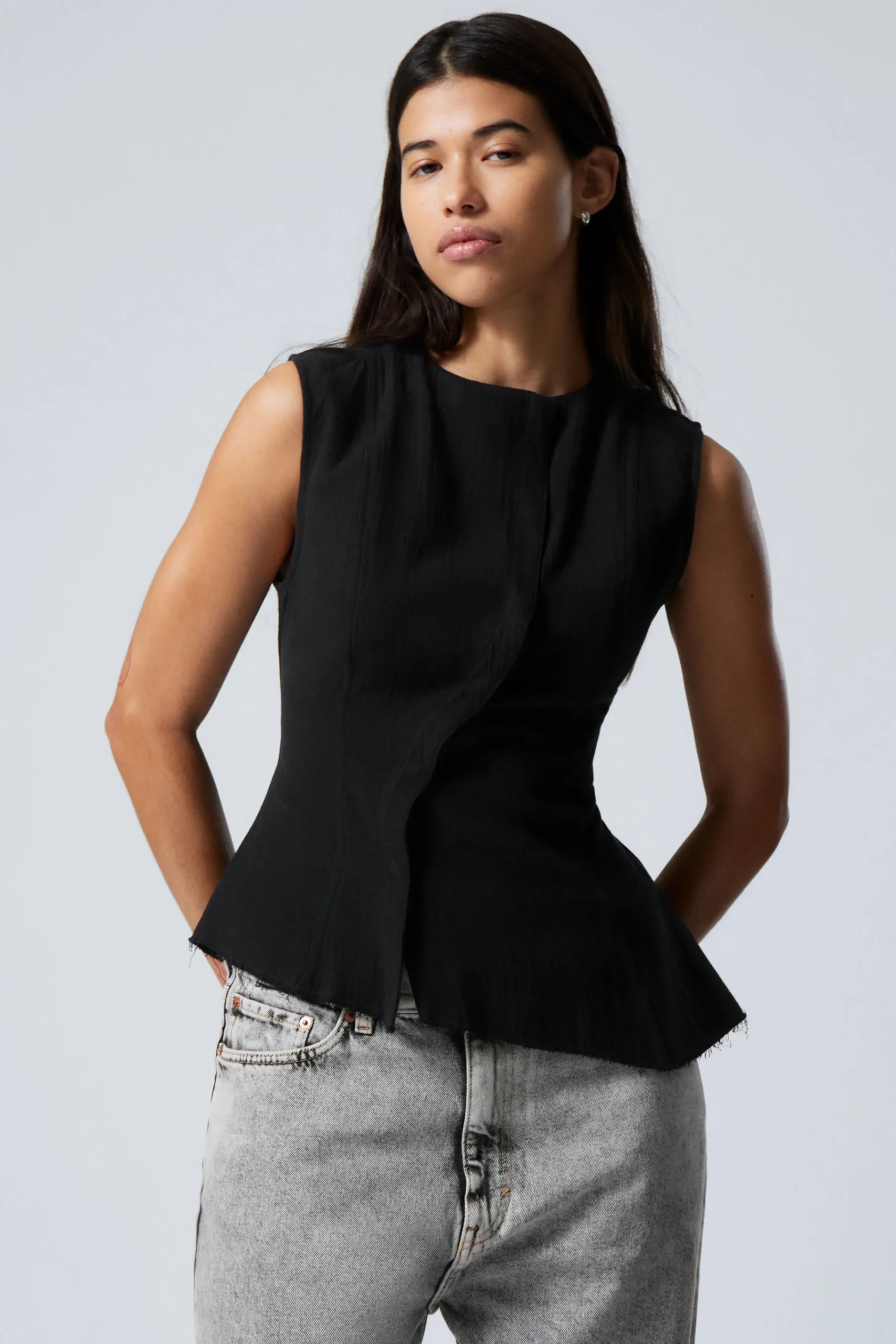 rmls_asymmetrisk_peplum_topp_0-1.webp Weekday Toppar<ÄRMLÖS ASYMMETRISK PEPLUM TOPP